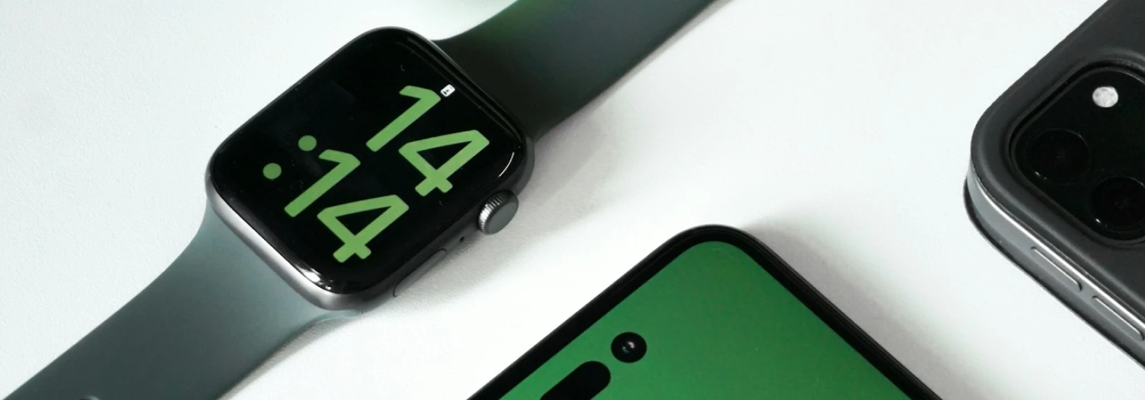 An Apple Watch and two phones lying on a white background